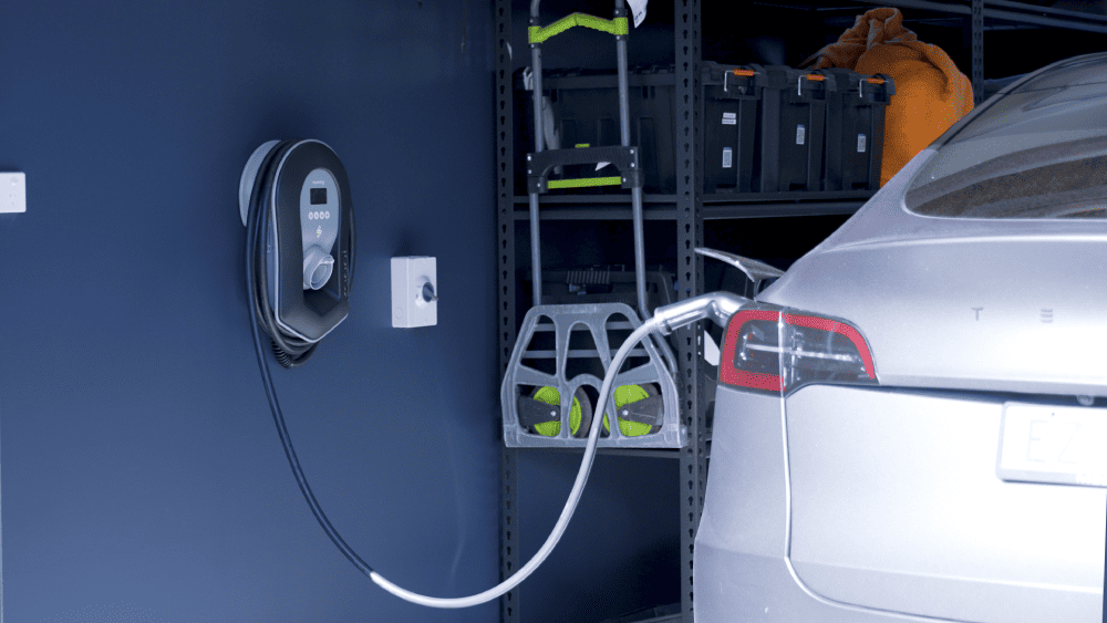 Wall-mounted EV charger installed next to electric car at residential property