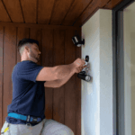 Electrician fitting an exterior wall light near a home entrance