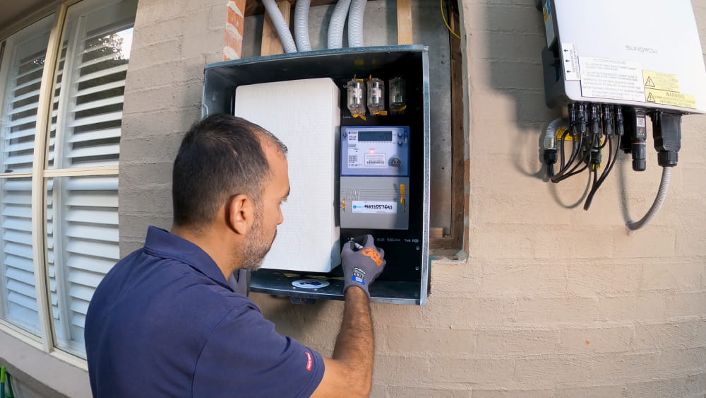 Electrician installing and testing a new electrical meter in outdoor meter box