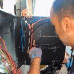 Electrician working on meter panel wiring inside outdoor electrical box