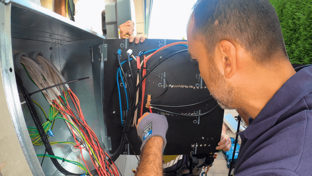 Electrician working on meter panel wiring inside outdoor electrical box