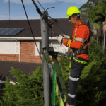 Level 2 electrician working on overhead electrical connection from ladder