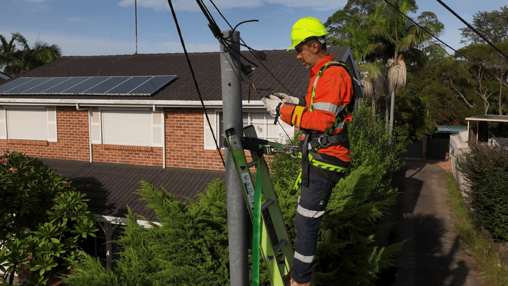 Level 2 electrician working on overhead electrical connection from ladder