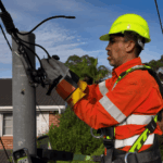 Level 2 electrician working on overhead power connection on a service pole