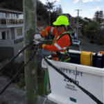 Electrician repairing overhead powerline cables from elevated work platform