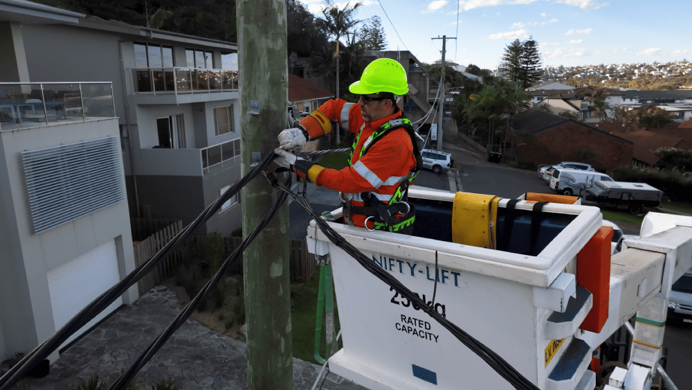 Electrician repairing overhead powerline cables from elevated work platform