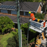 Electrician using elevated platform for overhead powerline repair near home