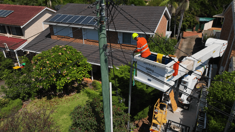 Electrician using elevated platform for overhead powerline repair near home