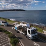 IZCO Electrical fleet and elevated lift truck beside coastal overhead powerline area