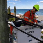 Level 2 electrician securing overhead service cables from elevated work platform