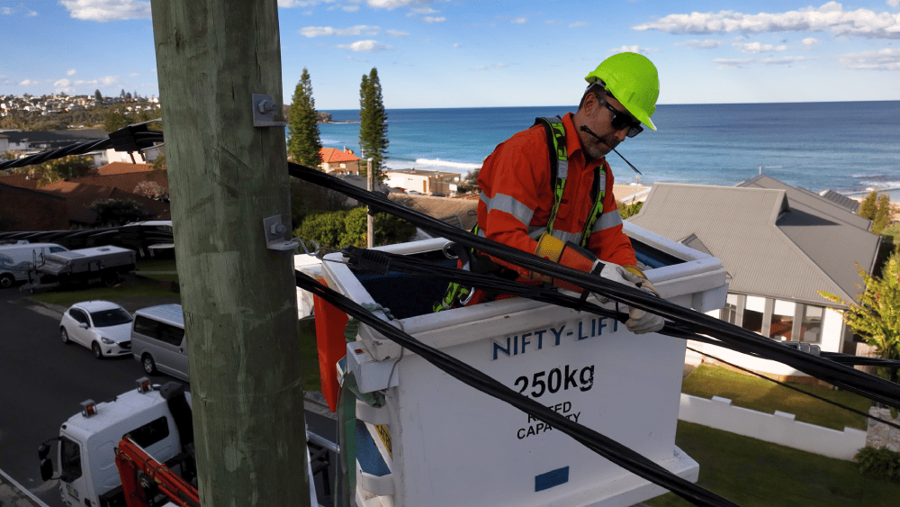 Level 2 electrician securing overhead service cables from elevated work platform