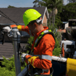 Electrician connecting overhead service cables on residential power pole