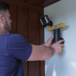 Electrician installing and adjusting outdoor security light on wall