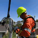 Electrician connecting overhead service line on residential power pole