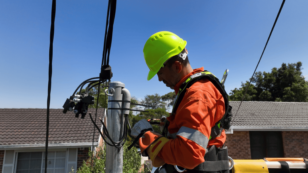 Electrician connecting overhead service line on residential power pole